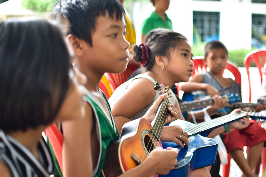 Street children learning to play ukulele and guitars