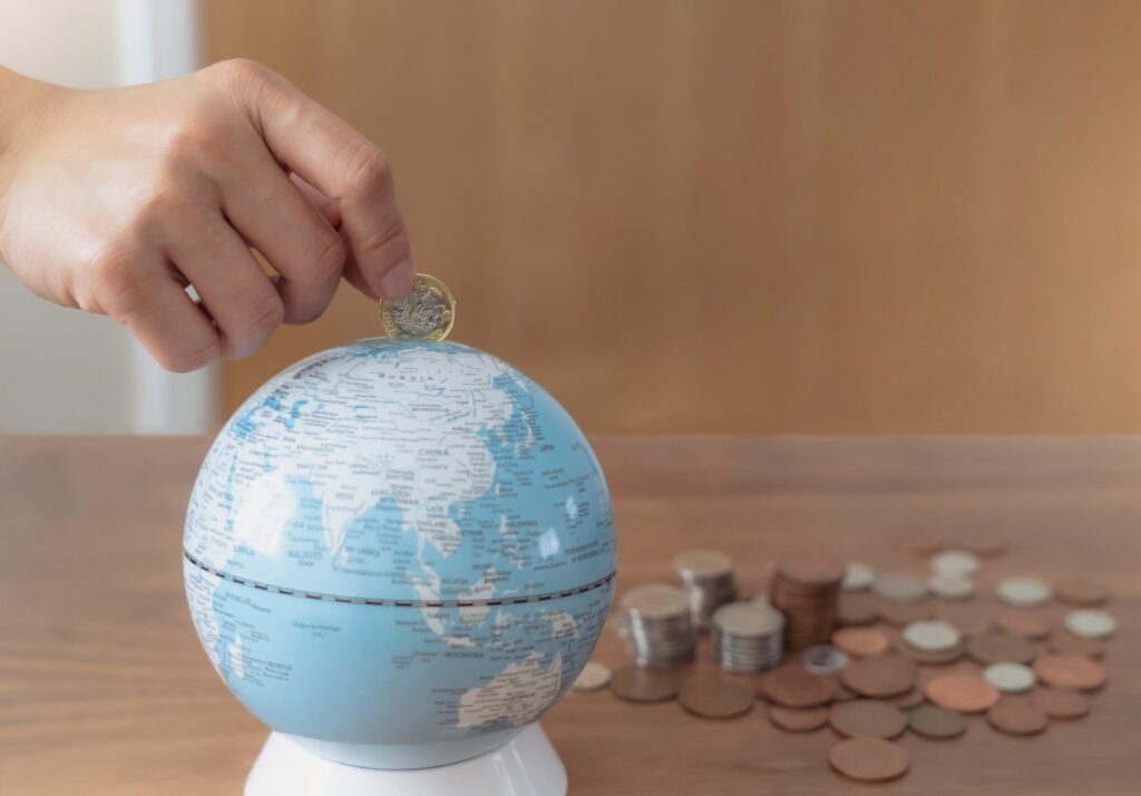 businesswoman hand putting one pound coin in to piggy bank for donate money