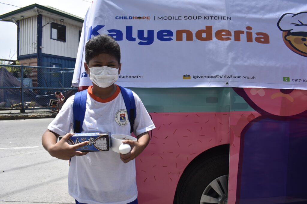 a boy poses in front of the mobile soup kitchen van