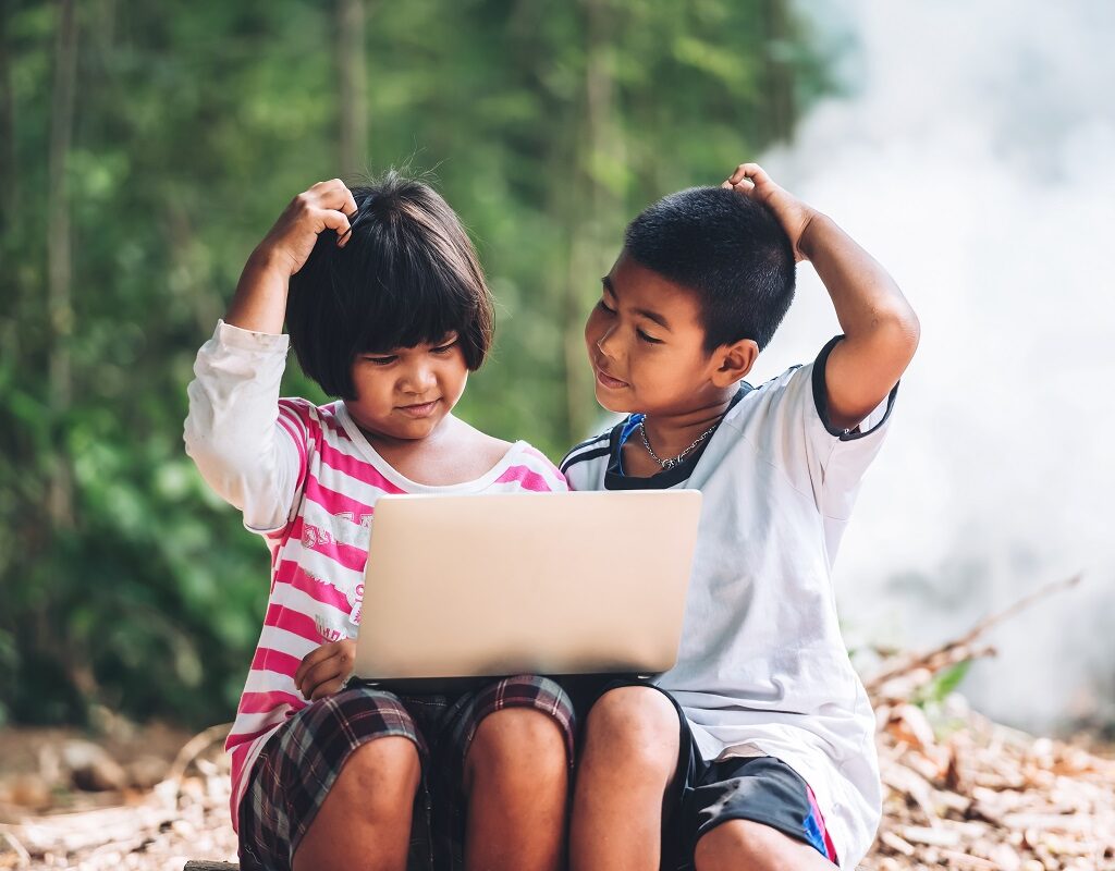 two Asian children studying via laptop