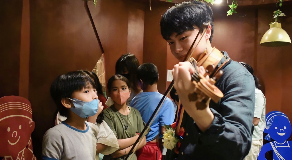 violinist Adrian Ong showing children how to play violin