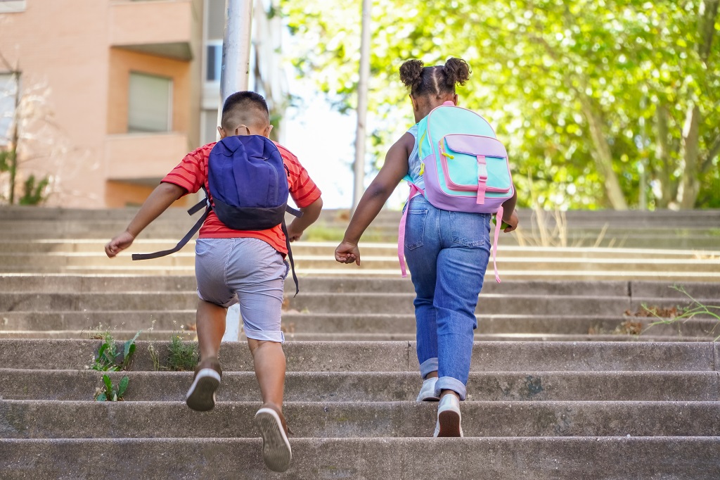 young students with backpacks happily walking to school together