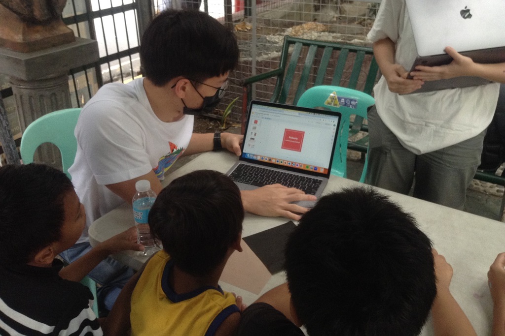 Childhope staff using laptop to teach children
