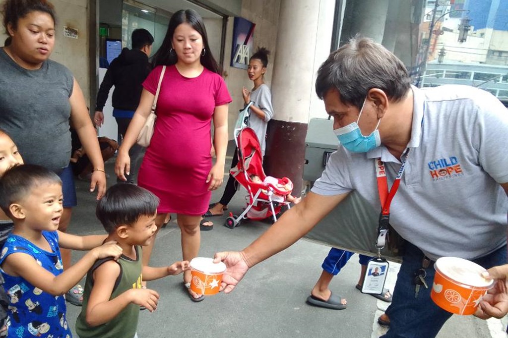 Childhope volunteer distributing free food to children