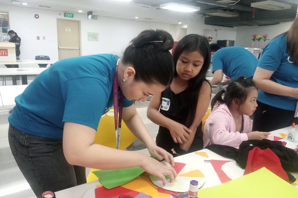 Childhope volunteers helping child beneficiaries learn basic arts