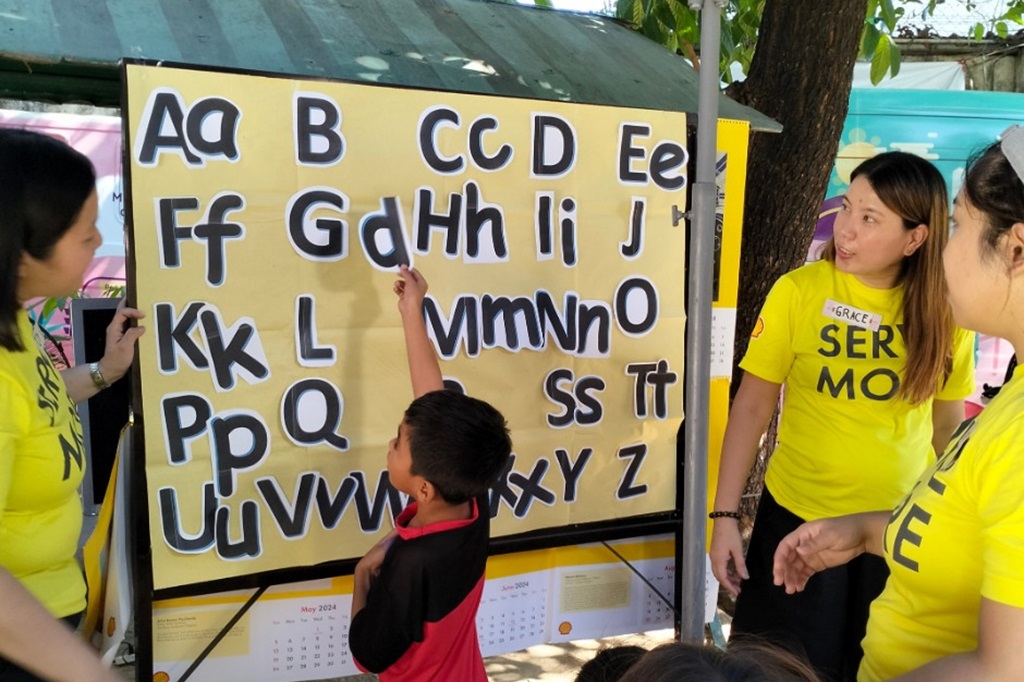 volunteers helping a child learn the alphabet